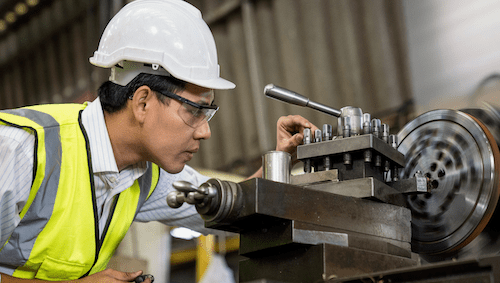 A mechanical engineer operating an industrial lathe machine
